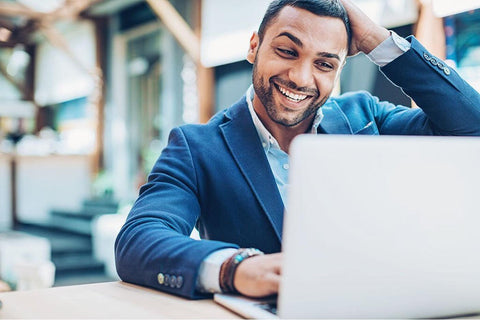 Excited African American Man, Scratching Head with Joy, Engaged on Laptop.