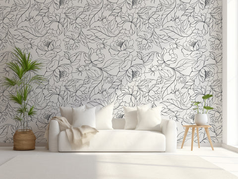 monochrome black and white leaves wallpaper design on wall of living room with white sofa and large green plant in front of it