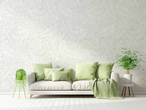 light pastel green leaves wallpaper in living room with pastel green and white couch with green plants either side of the sofa