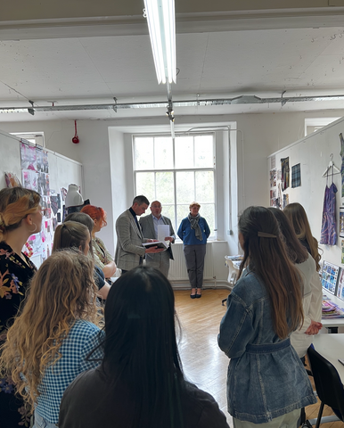 Iain Milligan, Managing Director of Huddersfield Fine Worsteds and Campbell Carey, Head Cutter and Creative Director at Huntsman (both centre frame), give feedback on student textile designs with Fiona Pankurst (far right), Assistant Professor in Woven Textile Design at Heriot-Watt School of Textiles and Design.