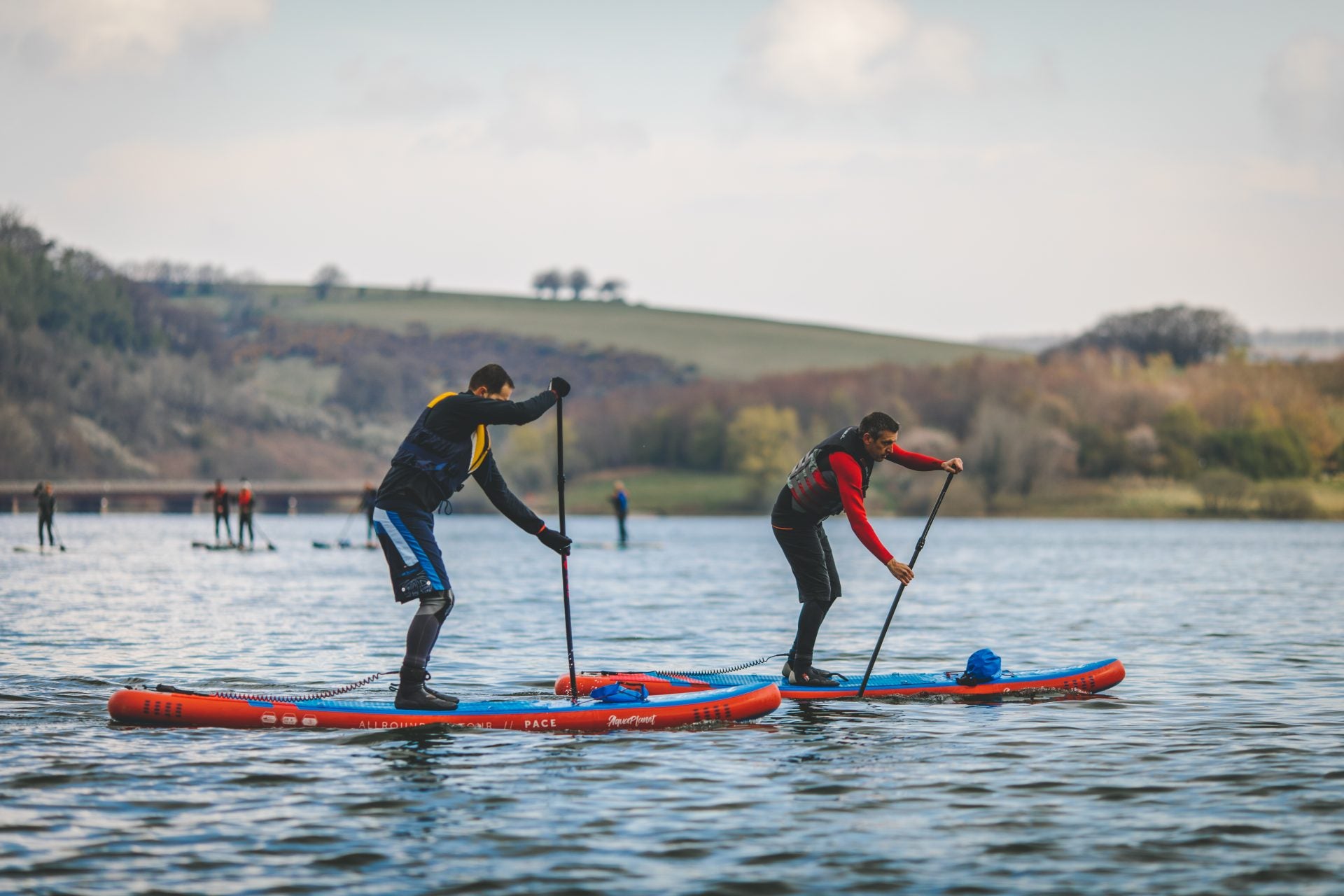 Two people on Aquaplanet PACE paddle boards racing each other