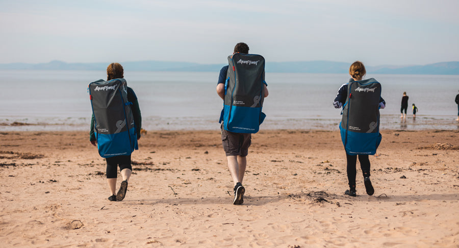 Group of people walking on beach wearing Aquaplanet SUP backpacks.