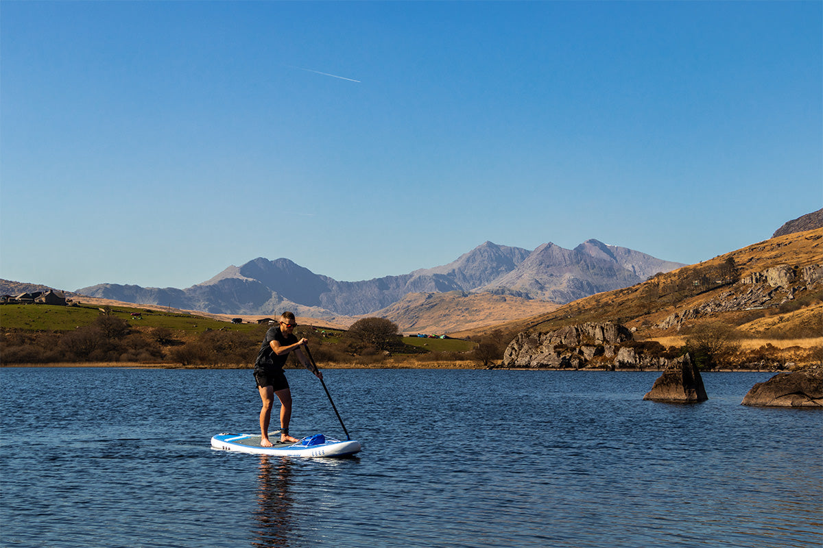 A person paddle boarding on a Blue MAX paddle board.