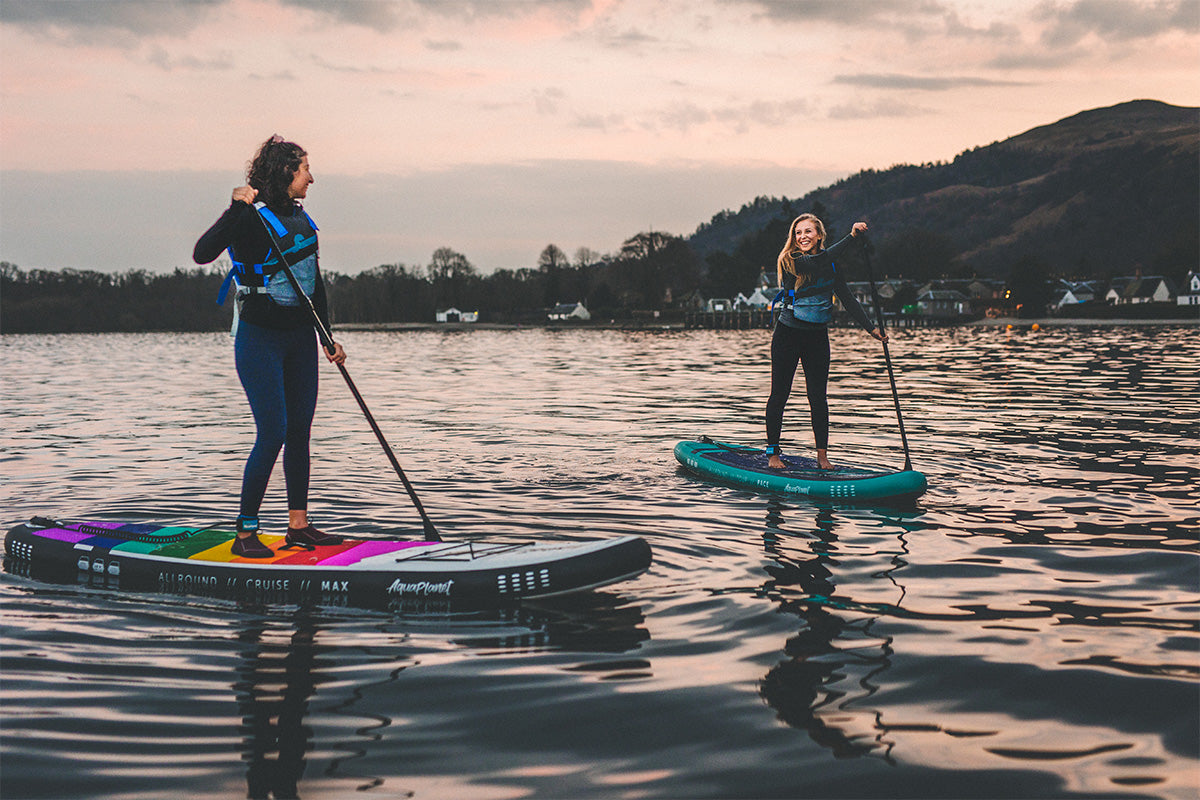 two people paddle boarding at sunset and talking