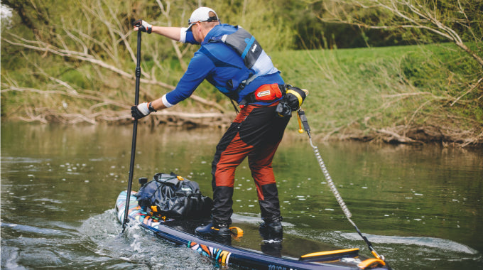 Someone paddle boarding on a Hurley colorwave paddle board wearing Aquaplanet safety equipment.