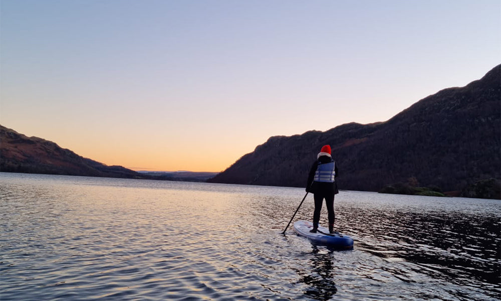 a woman paddle boarding dressed for the cold