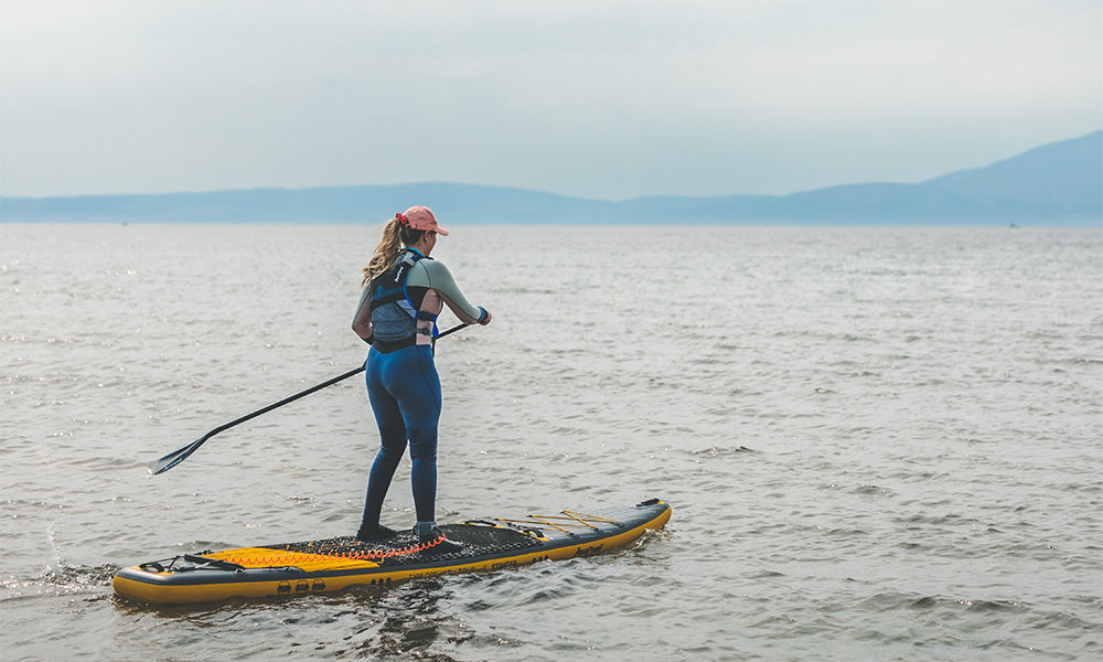 A woman paddle boarding on the Aquaplanet Stinger