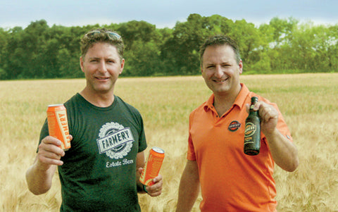 Chris and Lawrence showcasing the premium Lager beer standing in the farm field