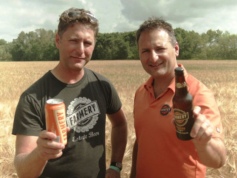 Chris and Lawrence on the farm holding the premium lager can and bottle