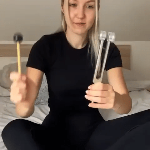 woman enjoys healing instrument tuning fork 128hz