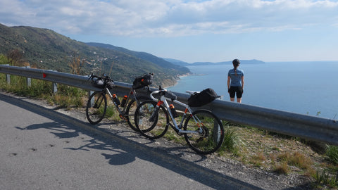two bikes propped up against a railing overlooking the sea