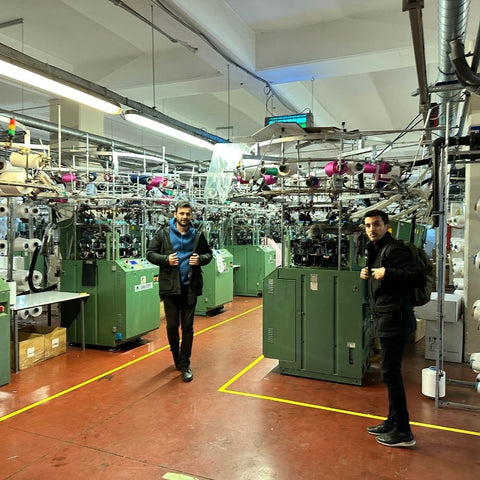 two men standing in front of giant machines that product clothing