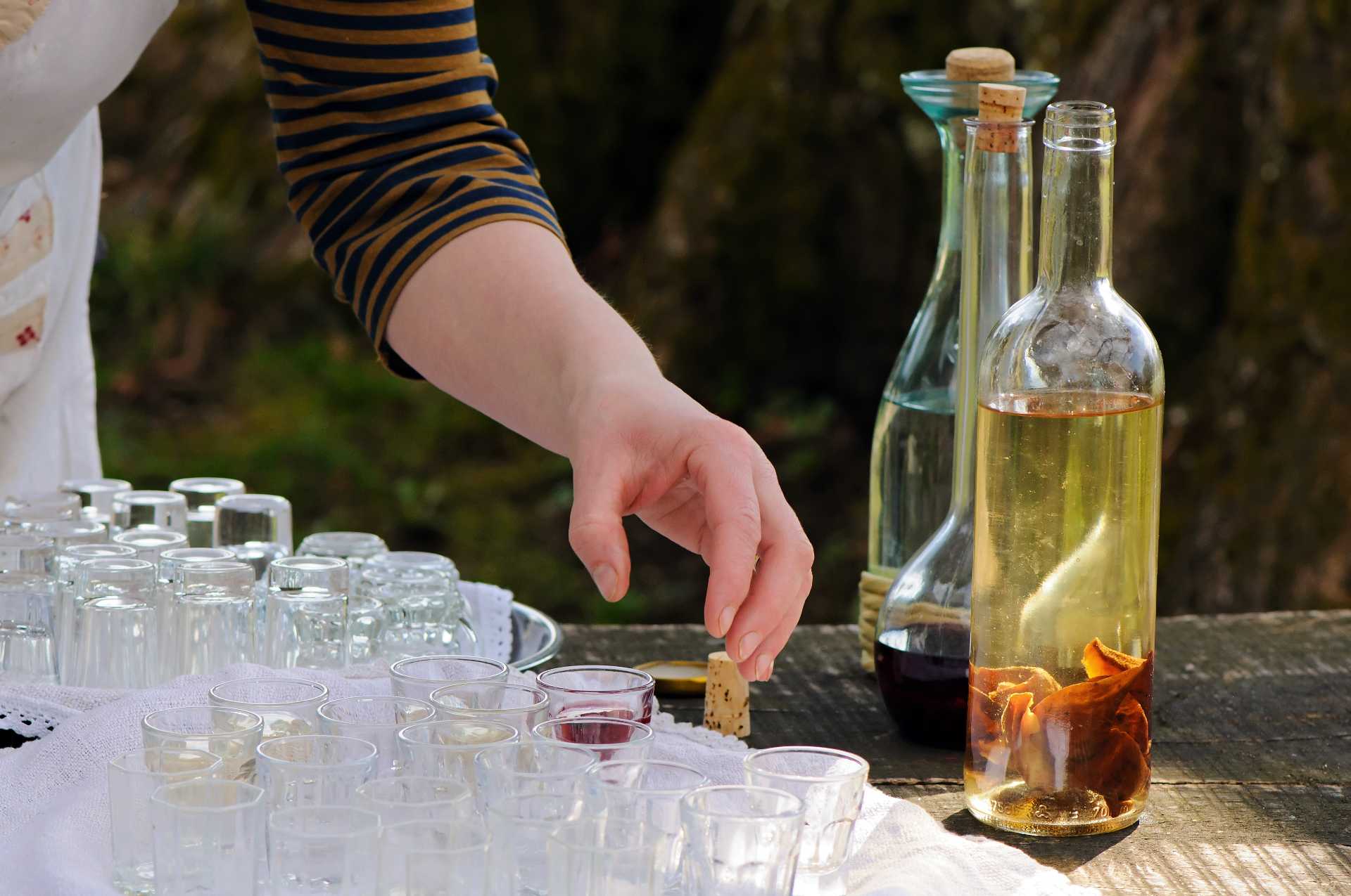 Table with tasting glasses and a bottle of infused alcohol, showcasing preparation and sampling.