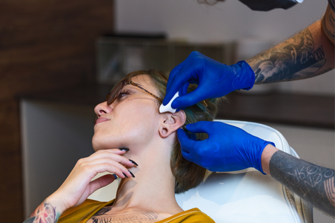 Piercing beim Durchstechen eines Helix-Piercings