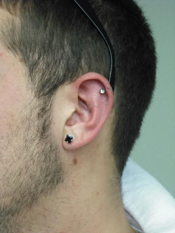 Close-up of a helix piercing on a male ear.