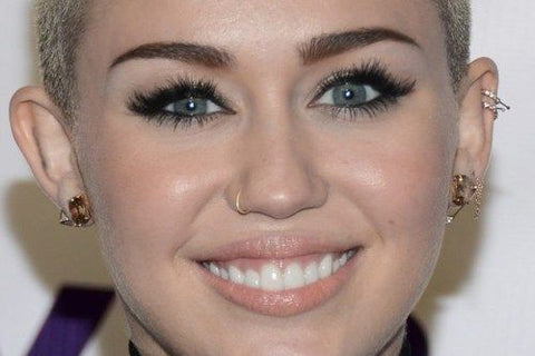 Miley Cyrus with a gold hoop helix piercing on her ear.