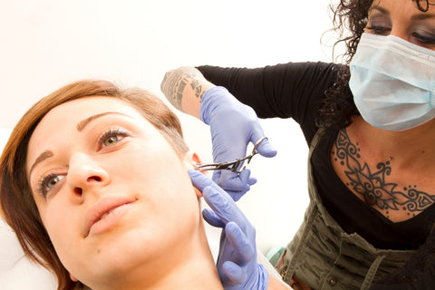 mulher recebendo um piercing feito por um profissional