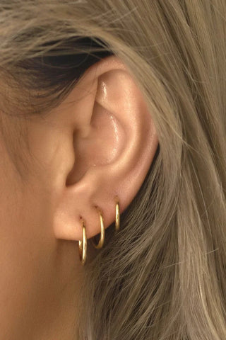 tres piercings aros dorados en la oreja
