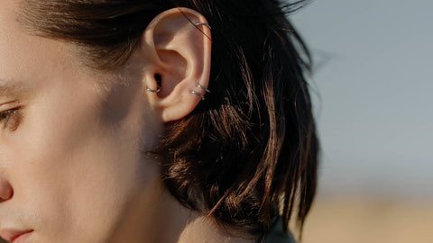 Piercing a woman's trago at the beach.