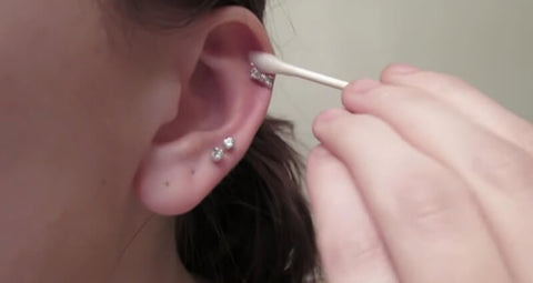 mujer cuida su piercing de la oreja