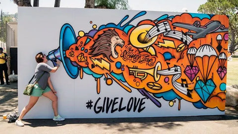 bảng graffiti màu sắc với hình ảnh sư tử và hashtag #givelove, cô gái đang tạo dáng bên cạnh