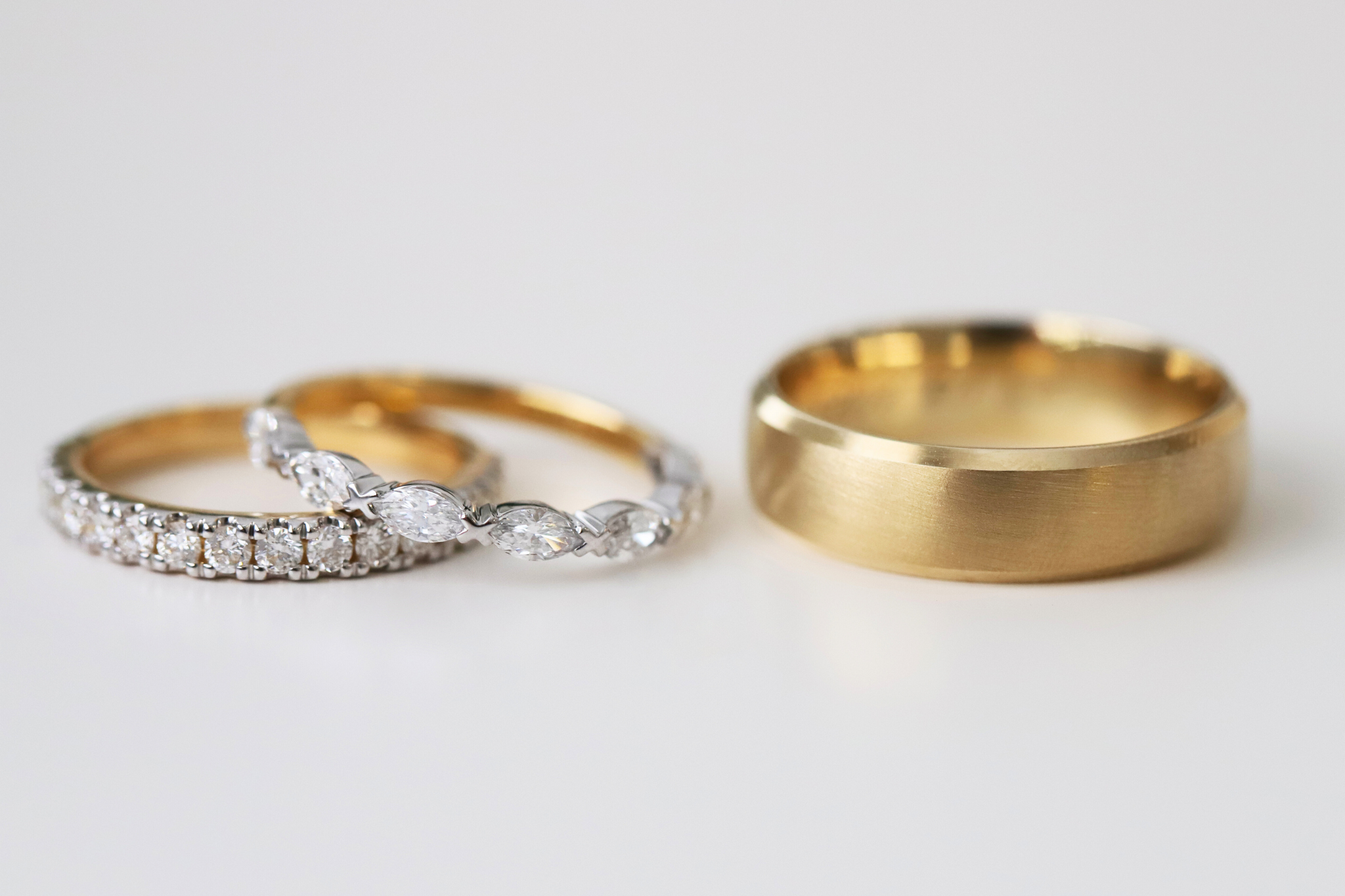 Two women's custom wedding rings with a men's plain gold wedding ring