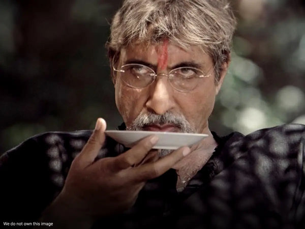 Amitabh Bachchan sipping chai in a movie scene.