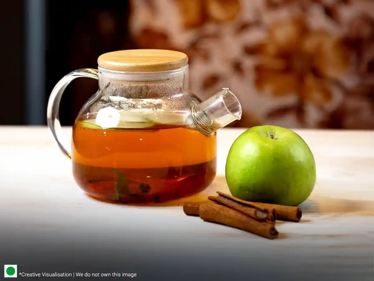 A cup of apple tea garnished with cinnamon sticks on the side