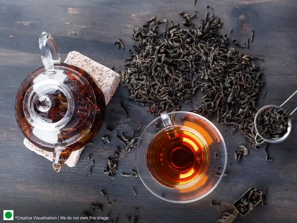 A cup filled with black tea that overflows with tea leaves