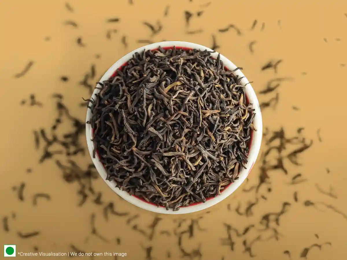 A bowl of spiced black tea with scattered leaves