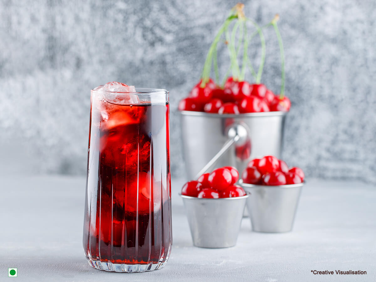 In a glass filled with ice cubes, there’s cranberry iced tea & berries. Behind there are 3 small buckets of cranberries.