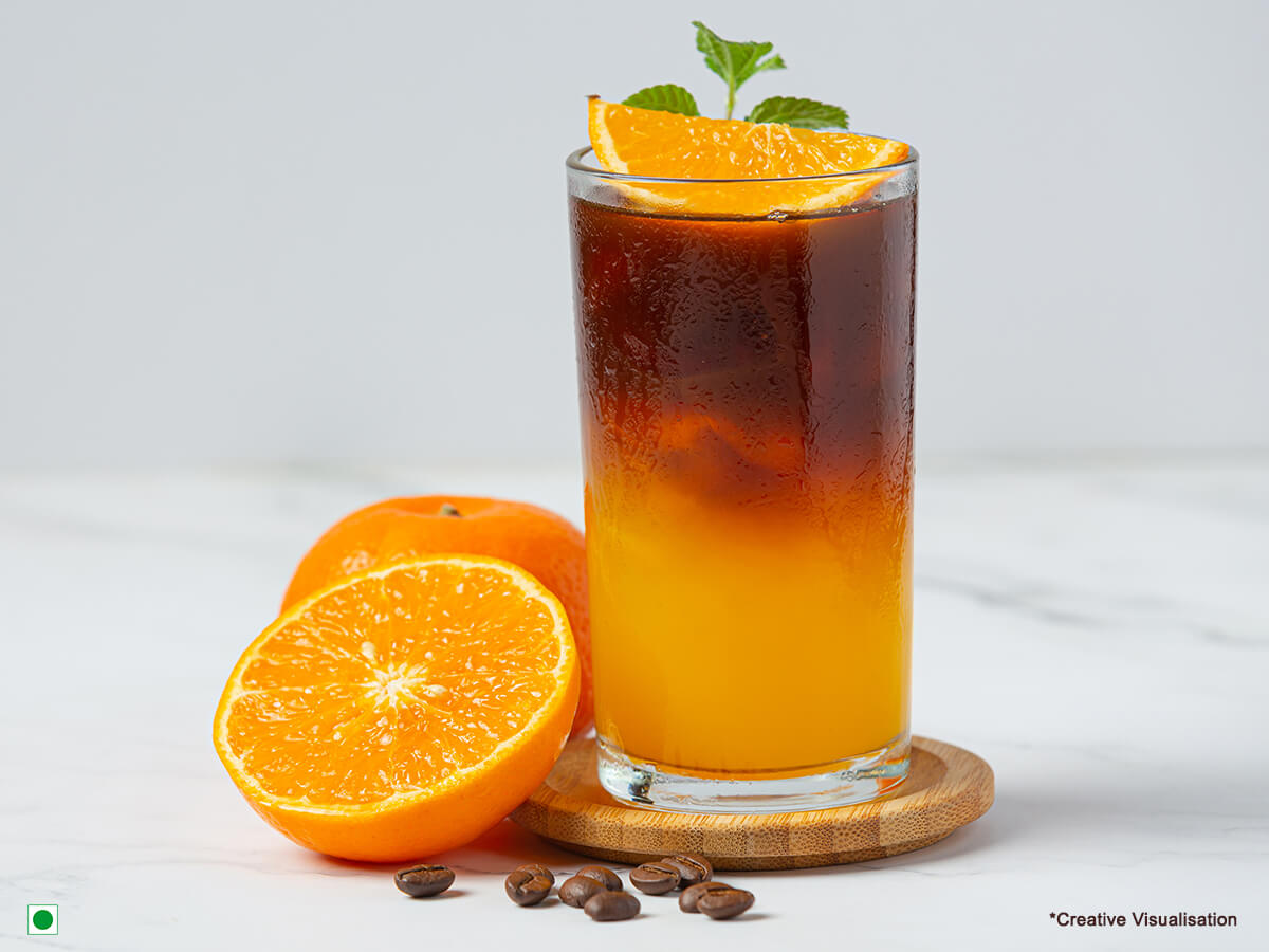 A jar of orange iced tea filled with ice cubes and garnishes with mint.