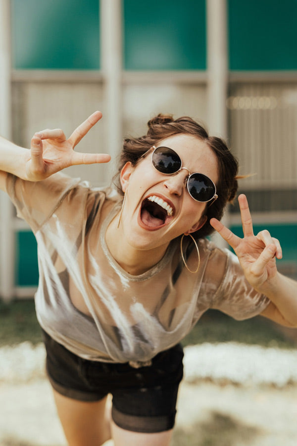 Gut gelaunte Studentin mit Sonnenbrille die Peace Zeichen mit ihren Händen macht