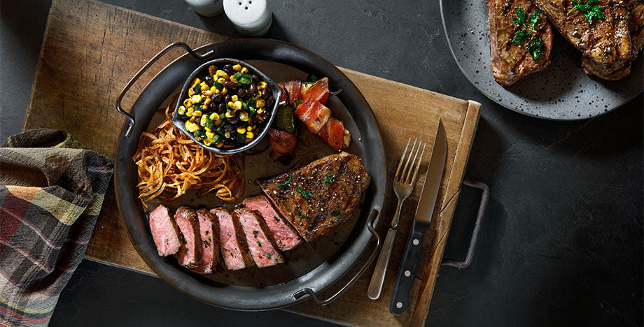 sliced striploin steak with side of corn salsa and bacon