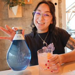 Rose posing with Rosie the Riveter cocktail and bottle of Freeland Gin