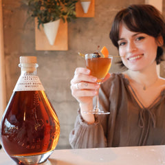 Grace posing with her cocktail Femme Fatale, next to bottle of Cask Strenght Bourbon