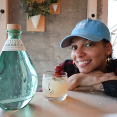 Kendra posing with her cocktail Artemis Moon, next to bottle of Forest Gin