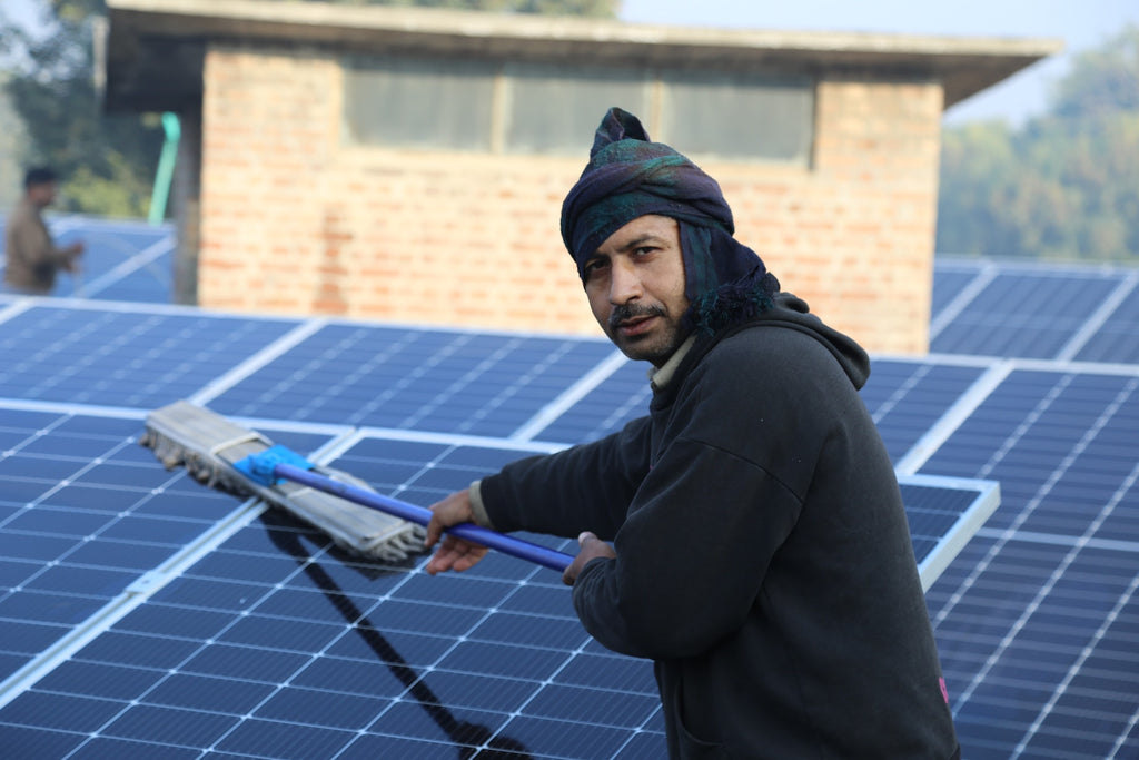 Ein Mann reinigt selber die Solarpanels auf dem Dach