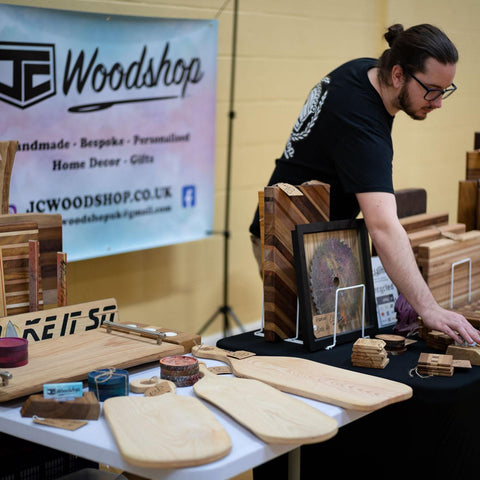 Jamie from JC Woodshop setting the display table at a craft fair.