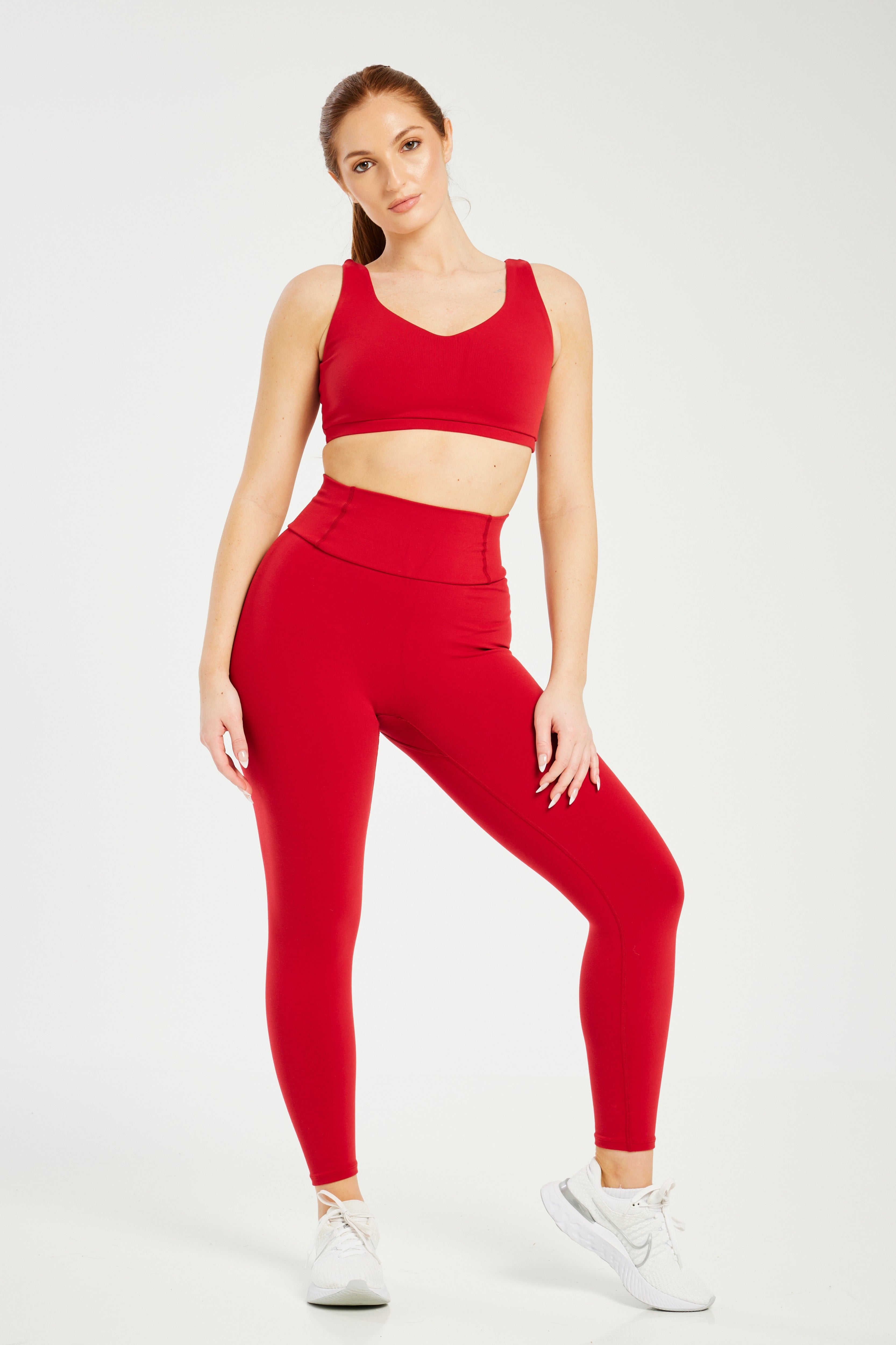 Woman in Red Sports Bra and Black Leggings Stretching · Free Stock Photo