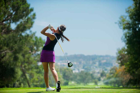 Une femme joue au golf avec sa casquette de golf performance.