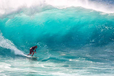 Un homme surf avec un chapeau surf.