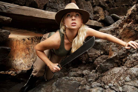 Une femme aventurière porte une machette et un bob dans une mine, en référence au film Indiana Jones.