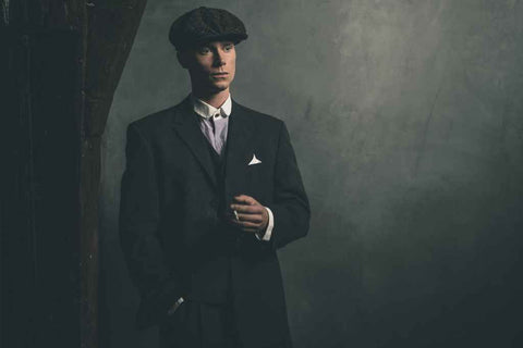 Un homme porte une casquette peaky blinders et est habillé comme la famille Shelby.