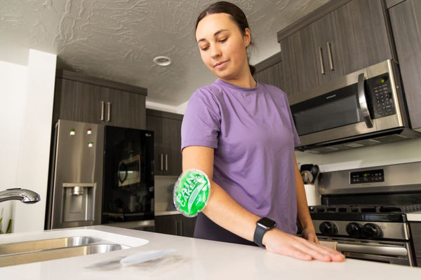 A woman with a cold pack on her elbow in a kitchen