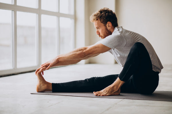 Man on a yoga mat stretching his leg