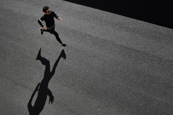 Above angle of a man running on black pavement