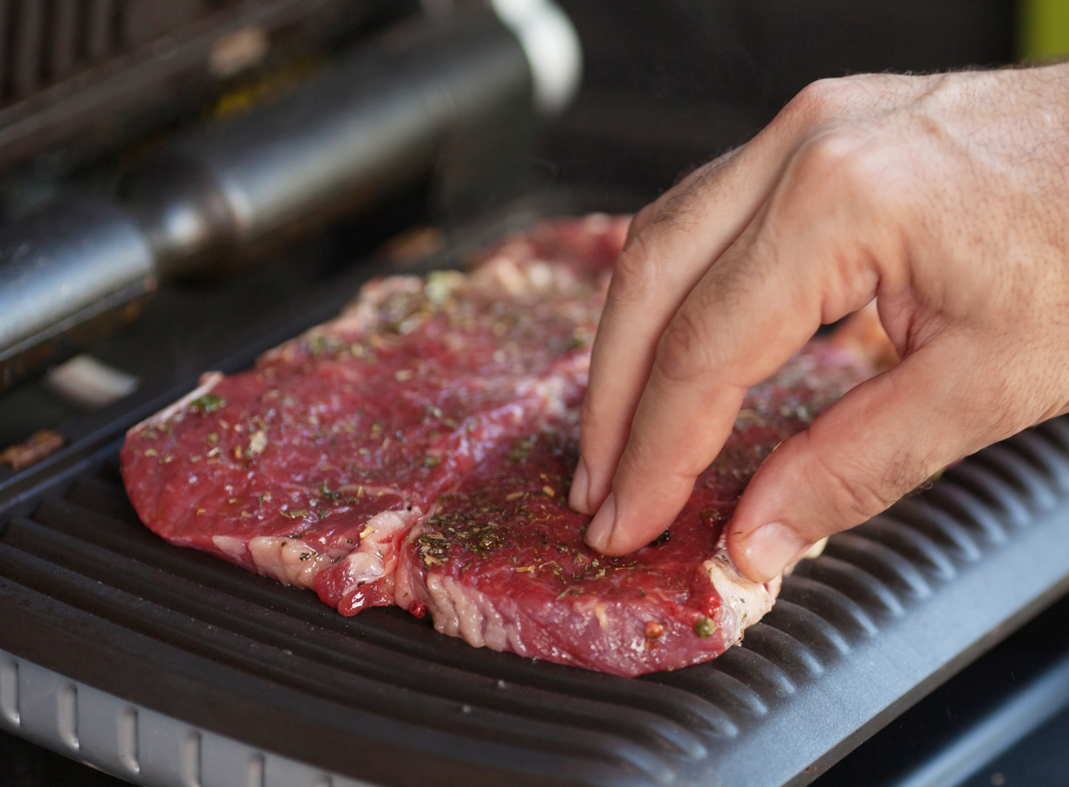 Seasoned steaks being grilled on an electric grill