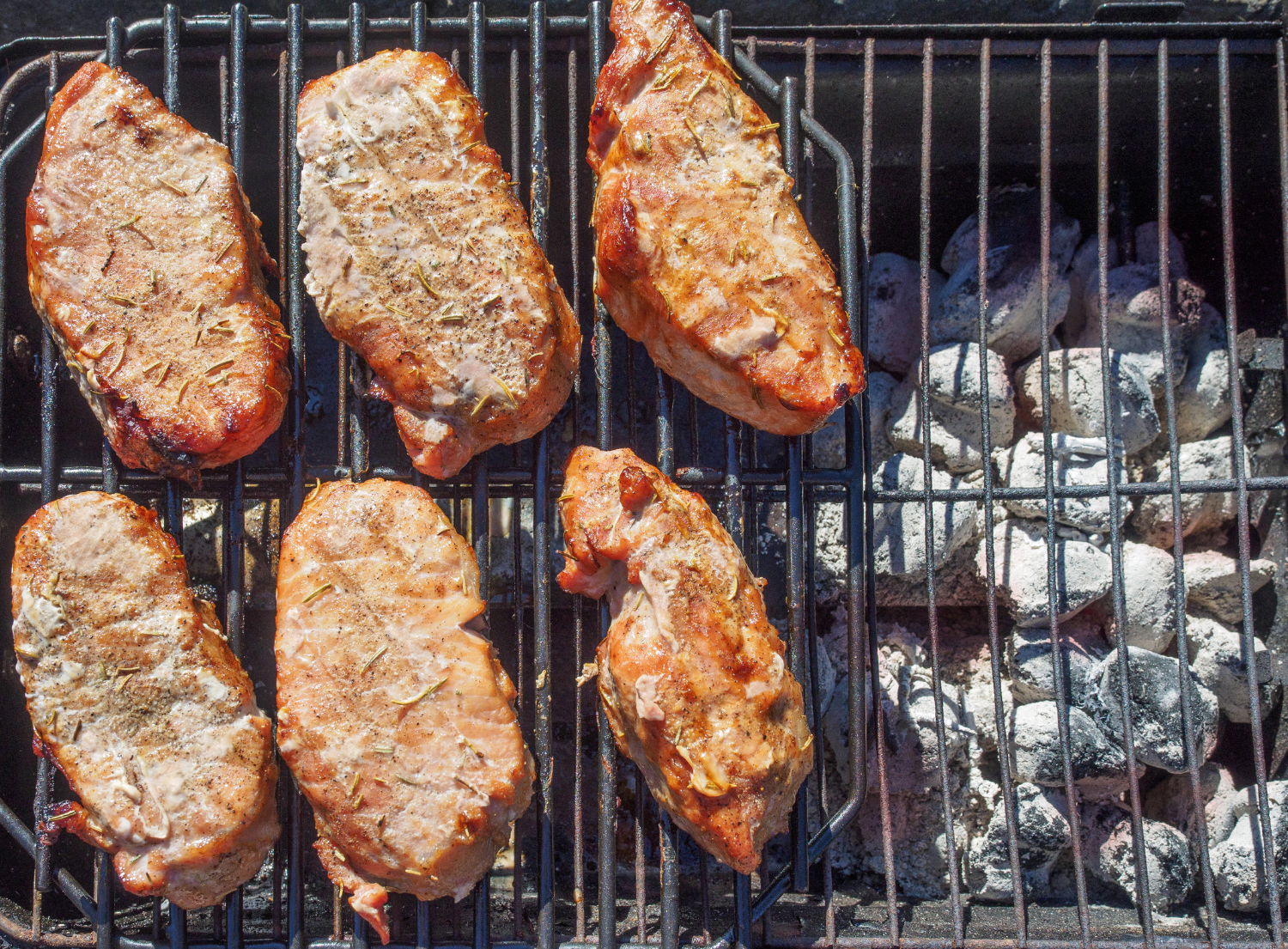 Meat being grilled. Charcoal is located on the right side of the grill and not underneath the meat. This is an example of indirect grilling