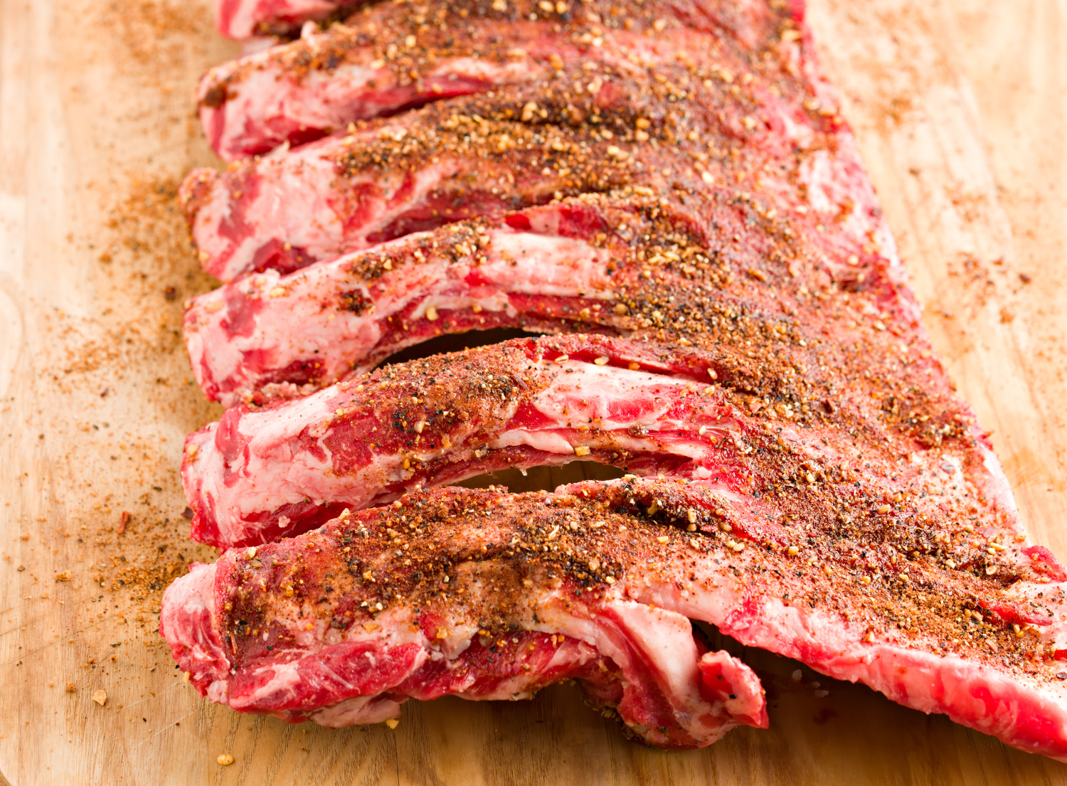 Uncooked rack of ribs with dry rub dusted on top before they are grilled